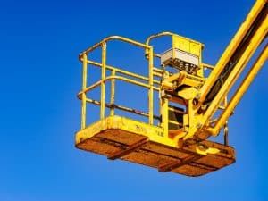 A yellow elevated work platform (EWP) basket against a bright blue sky, highlighting the importance of EWP training accreditation for safe operation.