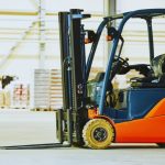 Modern warehouse forklift used for training on different types of forklift licences, parked indoors with stacked pallets nearby.