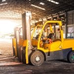 A bright yellow forklift, one of the many types of forklifts, sits in a warehouse ready for work.