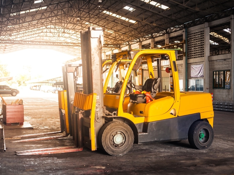 A bright yellow forklift, one of the many types of forklifts, sits in a warehouse ready for work.