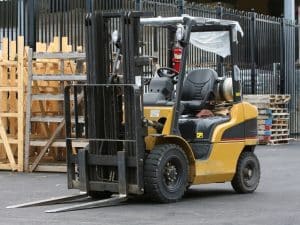 A yellow forklift, one of the many types of forklifts, stands ready for use in a storage yard with wooden pallets.