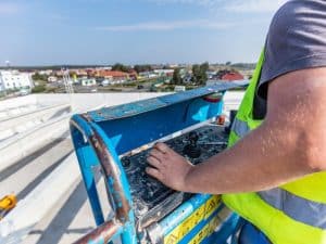 An ewp operator controls a blue elevated work platform high above the ground.